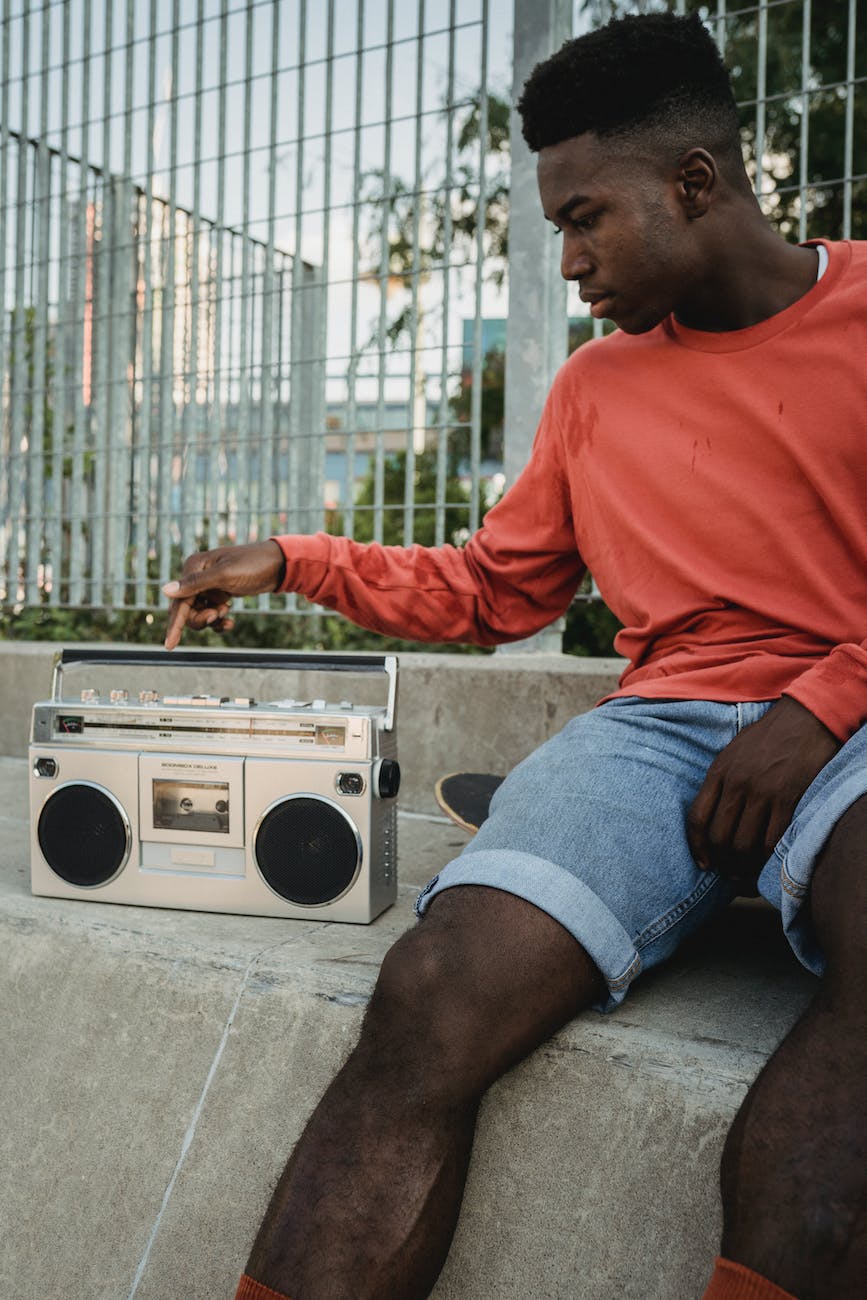 black skateboarder pressing button on retro tape recorder on street